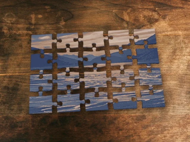 Printed jigsaw puzzle of a mountain lake, pieces spread out on a wooden table